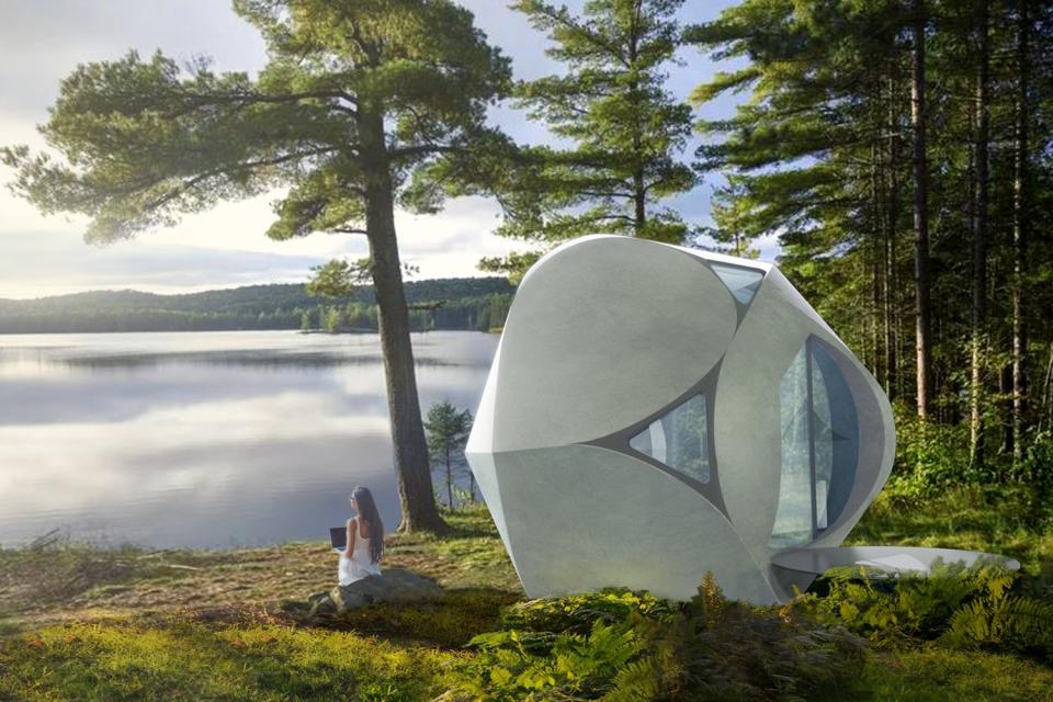 Woman works on a laptop on a rock beside a Serendix Partners 3D-printed housing pod.