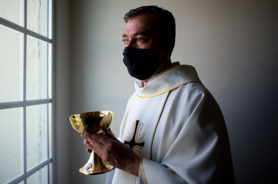 Father Andres Arango distributes Holy Communion while wearing a mask amid the COVID-19 pandemic at Gordon Hall at St. Gregory's Catholic Church in Phoenix on May 10, 2020.