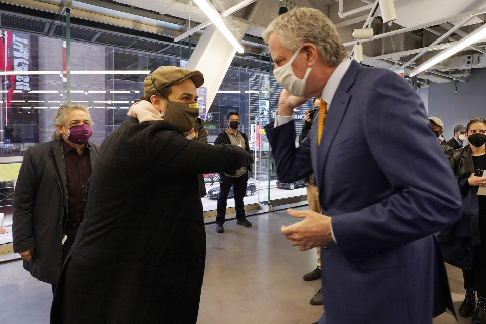 Actor Lin-Manuel Miranda, center, and New York Mayor Bill de Blasio, bump elbows before they tour the grand opening of a Broadway COVID-19 vaccination site intended to jump-start the city's entertainment industry, in New York, Monday, April 12, 2021. At left is Miranda's father. Luis A. Miranda, Jr. (AP Photo/Richard Drew, Pool)