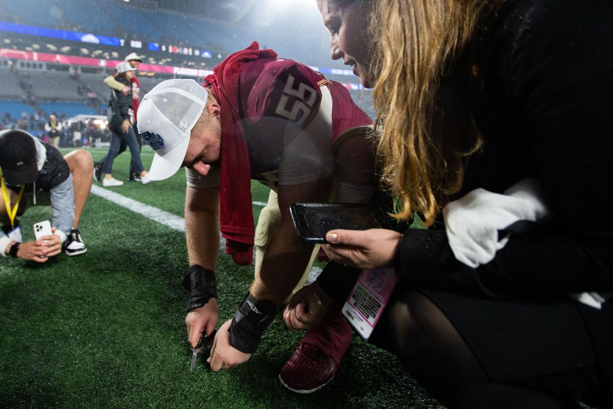 Florida State Seminoles defensive lineman Braden Fiske (55) cuts a piece of the turf after the game. The Florida State Seminoles defeated the Louisville Cardinals 16-6 to claim the ACC Championship title in Charlotte, North Carolina on Saturday, Dec. 2, 2023.