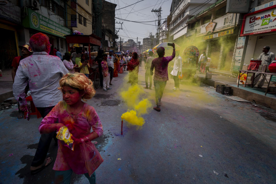 A girl throws collar powder during Holi, the festival of colors on a street in Guwahati, India, Wednesday, March 8, 2023.Millions of Indians on Wednesday celebrated the ''Holi" festival, dancing to the beat of drums and smearing each other with green, yellow and red colors and exchanging sweets in homes, parks and streets. Free from mask and other COVID-19 restrictions after two years, they also drenched each other with colored water. (AP Photo/Anupam Nath)