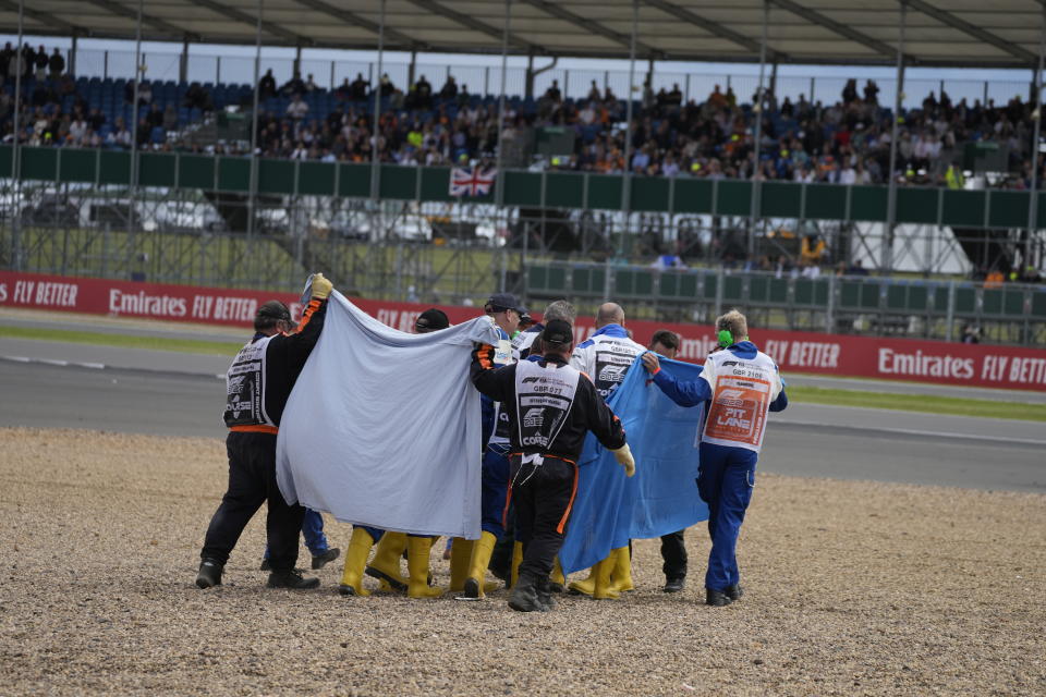 Alfa Romeo driver Guanyu Zhou of China, centre, receives medical treatment after he was involved in a crash at the start of the British Formula One Grand Prix at the Silverstone circuit, in Silverstone, England, Sunday, July 3, 2022. (AP Photo/Frank Augstein)