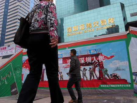Passers-by walk on a footbridge in front of the Shenzhen Stock Exchange, China January 5, 2011. REUTERS/Bobby Yip/ File Photo
