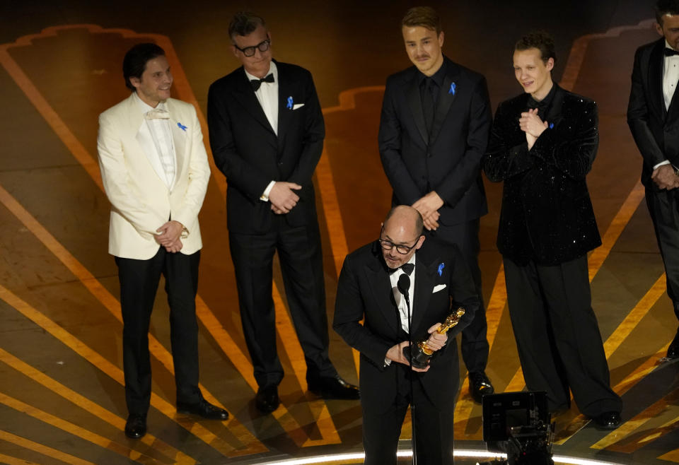 Edward Berger, forward center, accepts the award for "All Quiet on the Western Front" from Germany, for best international feature film at the Oscars on Sunday, March 12, 2023, at the Dolby Theatre in Los Angeles. Standing from left are Daniel Bruhl, Malte Grunert, Albrecht Abraham Schuch and Felix Kammerer.(AP Photo/Chris Pizzello)