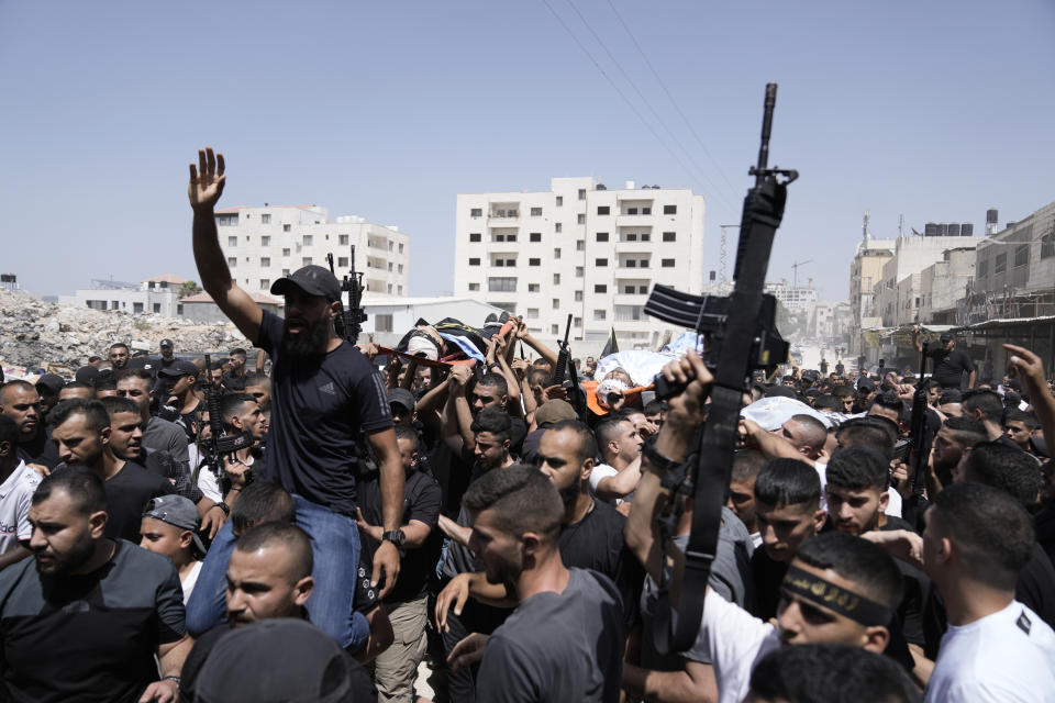 Gunmen march in the funeral for three people killed in an Israeli military operation, in Jenin refugee camp in the West Bank city of Jenin, Friday, July 5, 2024. The Israeli military said Friday it was conducting counterterrorism activity that included an airstrike in the area of the West Bank city of Jenin. Palestinian authorities said five people were killed. (AP Photo/Majdi Mohammed)