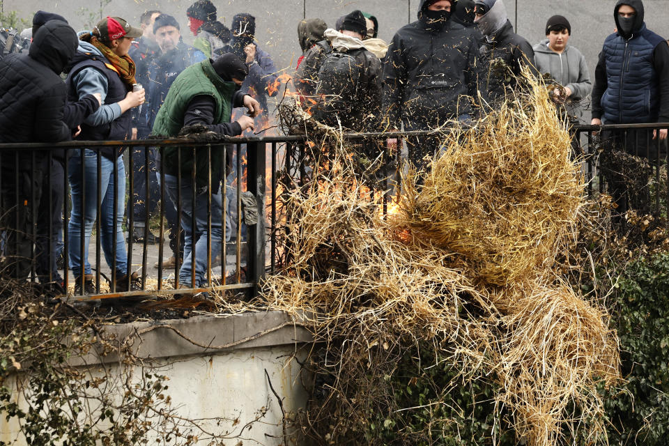 Protesting farmers throw a burning bale of hay off of a small overpass near the European Council building in Brussels during a demonstration of farmers, Tuesday, March 26, 2024. Dozens of tractors sealed off streets close to European Union headquarters where the 27 EU farm ministers are meeting to discuss the crisis in the sector which has led to months of demonstrations across the bloc. (AP Photo/Geert Vanden Wijngaert)