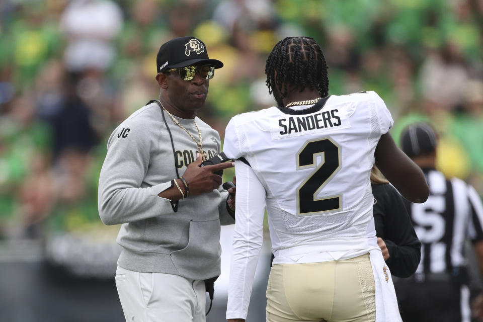 Colorado head coach Deion Sanders talks with his son and quarterback Shedeur Sanders during the first half of an NCAA college football game against Oregon, Saturday, Sept. 23, 2023, in Eugene, Ore. (AP Photo/Amanda Loman)