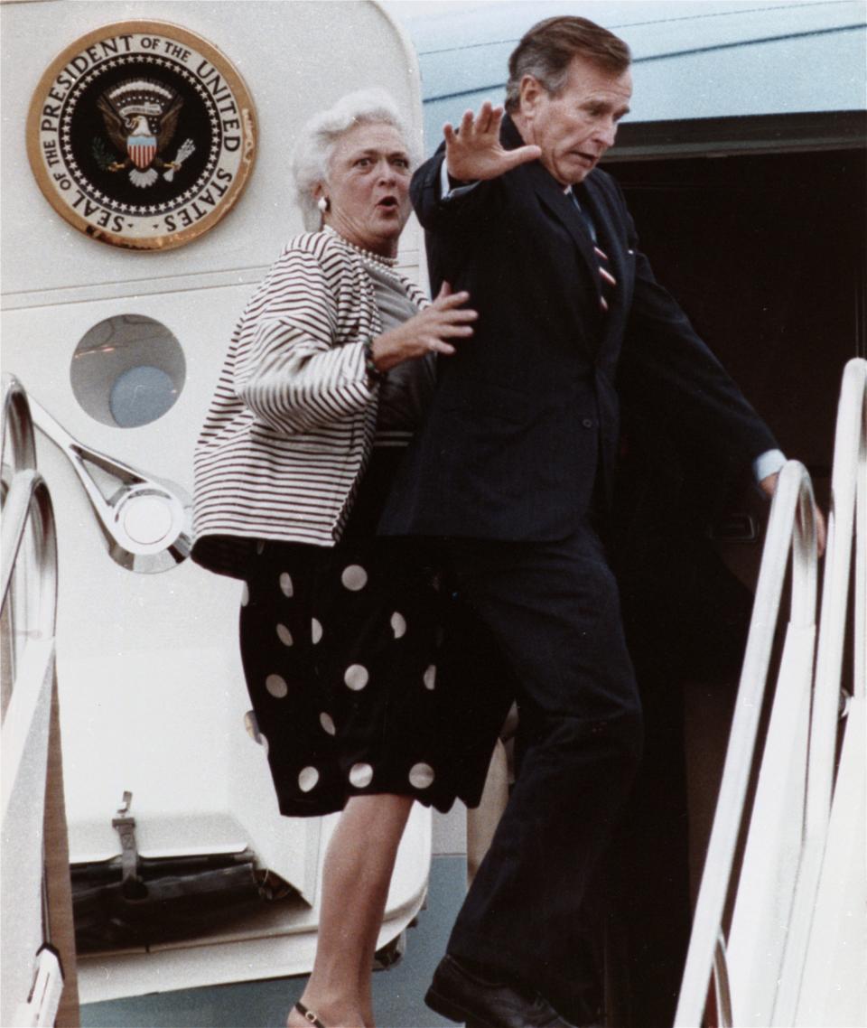 FILE - In this Sept. 22, 1989, file photo, first lady Barbara Bush reacts after President George H.W. Bush accidentally stepped on her toe while boarding Air Force One at Andrews Air Force Base, Md., for a flight to New Jersey. Both Bushes have been hospitalized this week in Houston, where the former president is being treated for pneumonia and his wife for bronchitis. (AP Photo/Charles Tasnadi, File)