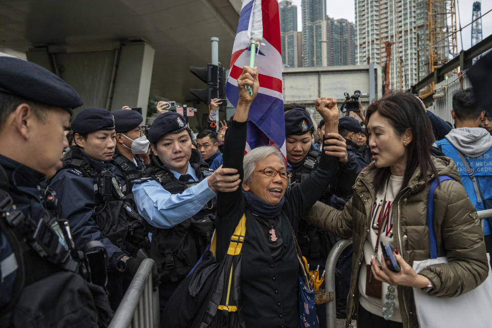 Activist Alexandra Wong, also known as Grandma Wong, is escorted into a barricade outside West Kowloon Magistrates' Courts, where activist publisher Jimmy Lai's trial is scheduled to open, in Hong Kong, Monday, Dec. 18, 2023. A landmark national security trial opened Monday in Hong Kong for prominent activist publisher Jimmy Lai, who faces a possible life sentence if convicted under a law imposed by Beijing to crush dissidents. (AP Photo/Vernon Yuen)
