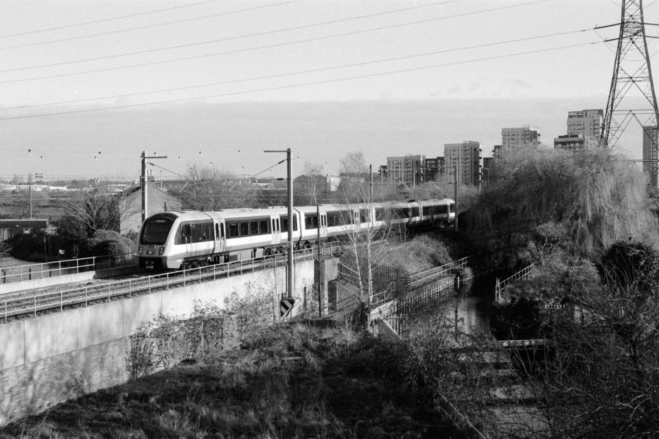 Train going over a bridge near some woodlands taken on Ilford HP5 Plus 35mm film