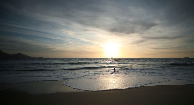 FILE PHOTO: A lone bather takes in the winter sun at a beach in Cape Town, South Africa, during the coronavirus disease (COVID-19) outbreak