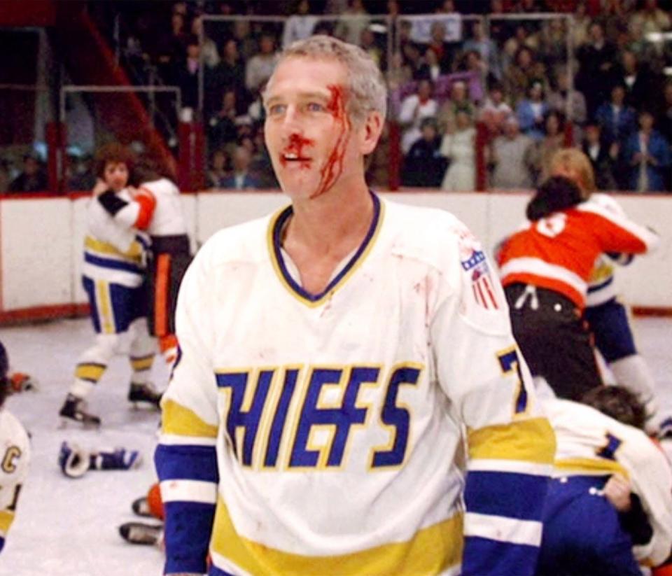 Paul Newman in a hockey uniform with blood on his face