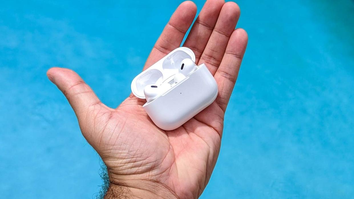  Apple AirPods Por 2 USB-C in hand over a pool. 