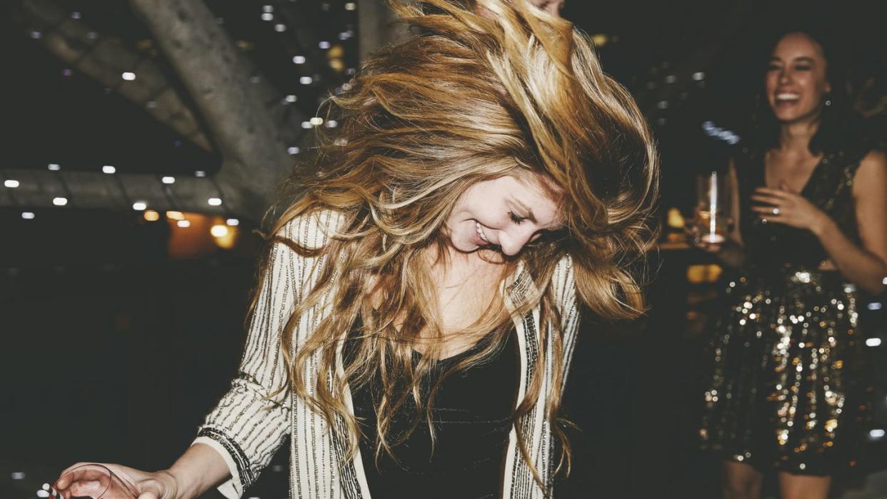 happy young woman tossing hair while dancing at party