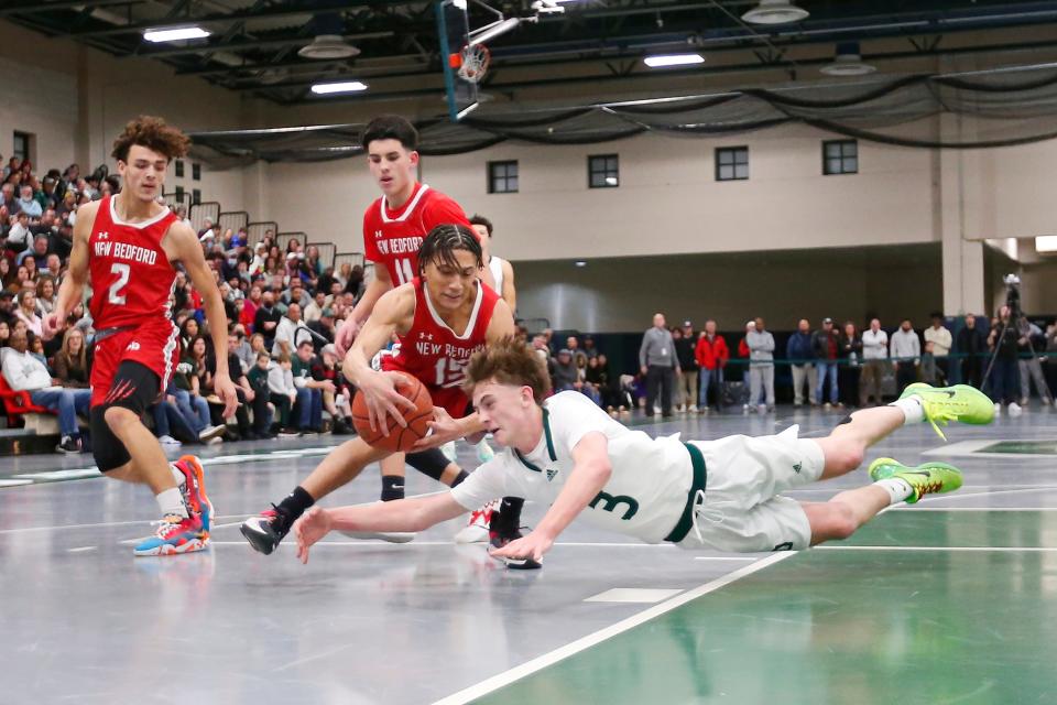Dartmouth's Aiden Smith dives for the ball New Bedford's Joseph Anderson maintains possession. Dartmouth High School boys' basketball team beat New Bedford High School at home.