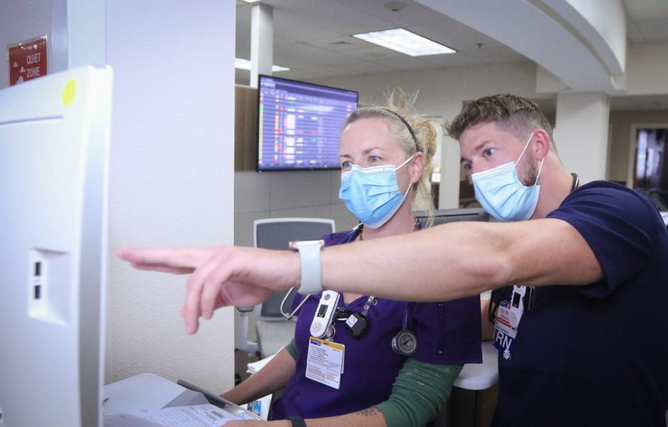 Nurses Jennifer Royce and Patrick Noone discuss a patient’s status in the Progressive Care Unit at Health First Inc.'s Cape Canaveral Hospital in Cocoa Beach.