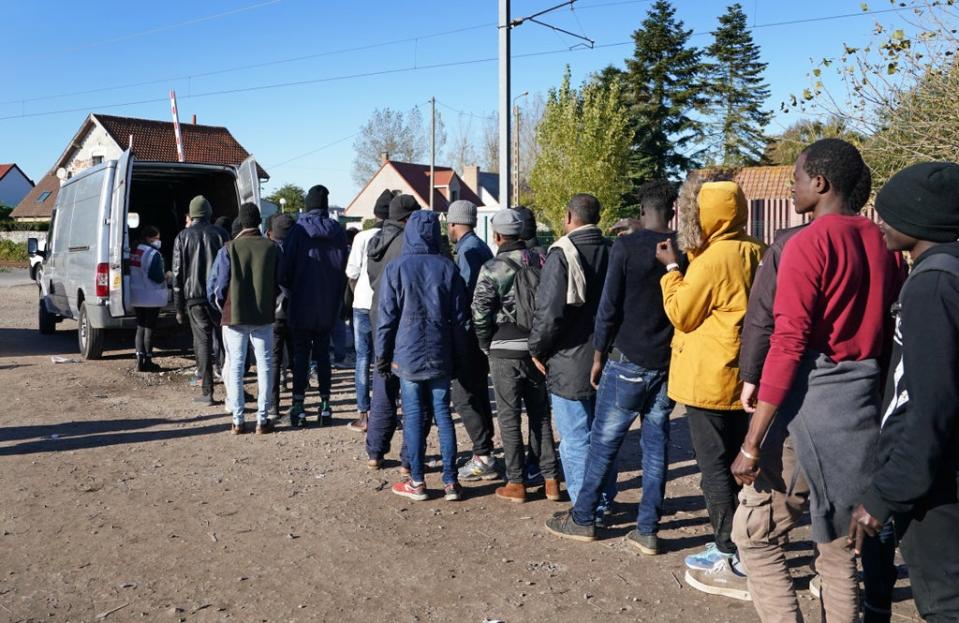 Migrants queue for food at a makeshift camp in Calais (Gareth Fuller/PA) (PA Wire)