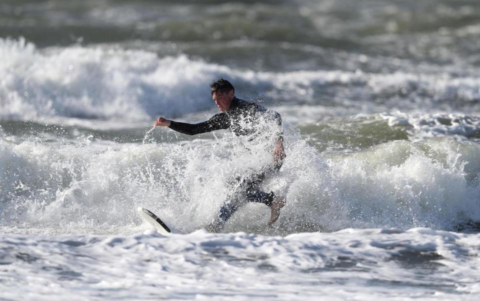 A surfer off West Wittering beach in West Sussex makes the most before the waves become too treacherous. (PA)