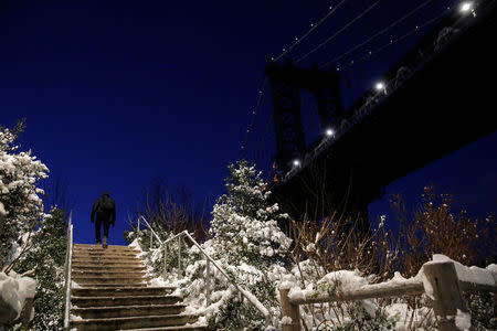 A man walks under the Manhattan Bridge following a snowstorm in Brooklyn, New York, U.S., February 9, 2017. REUTERS/Andrew Kelly