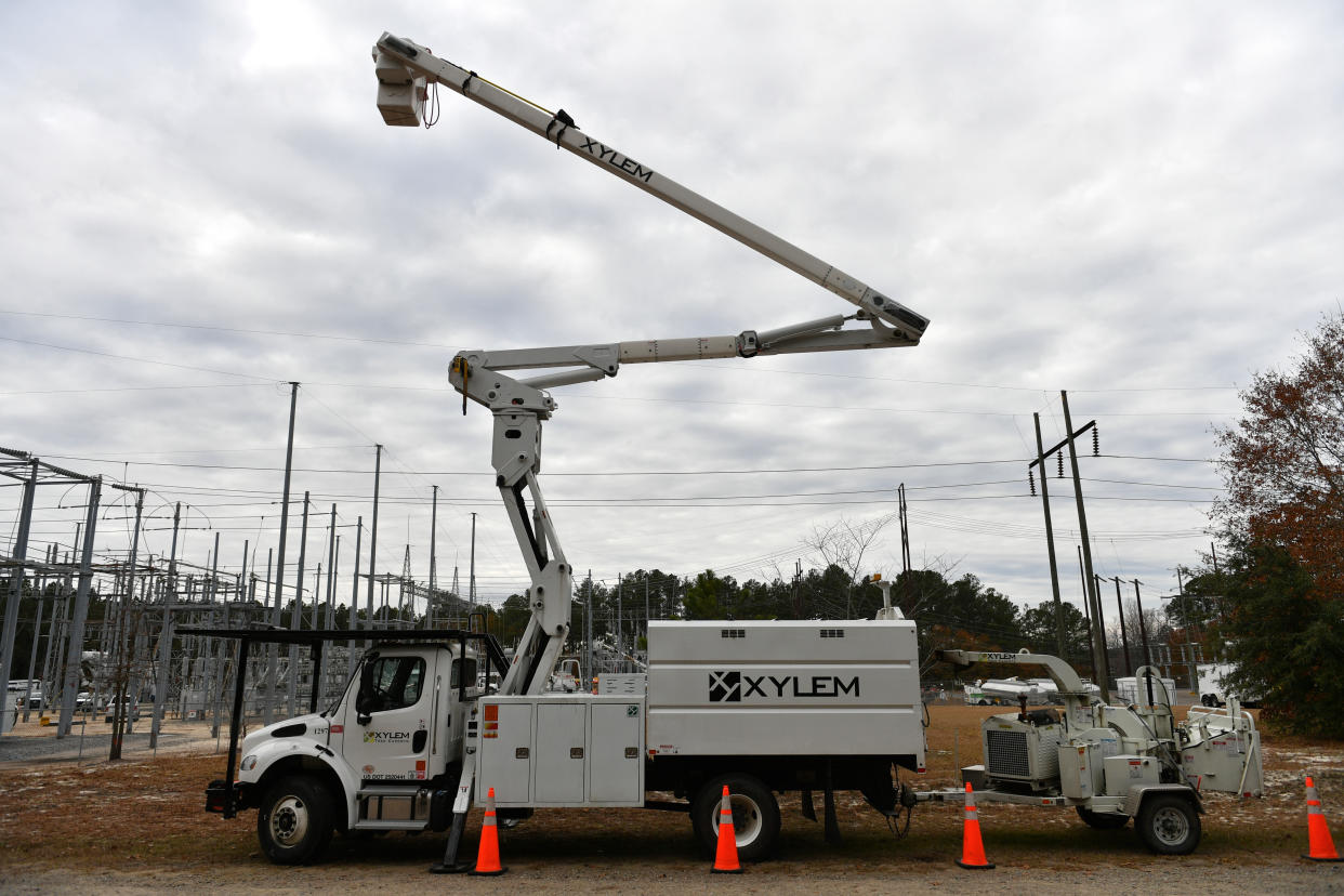 A crane mounted on a truck by a row of orange beacons.