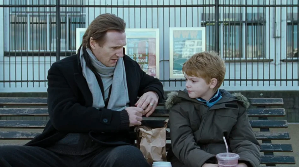 A photo still of Liam Neeson and Thomas Brodie-Sangster in Love Actually (2003).