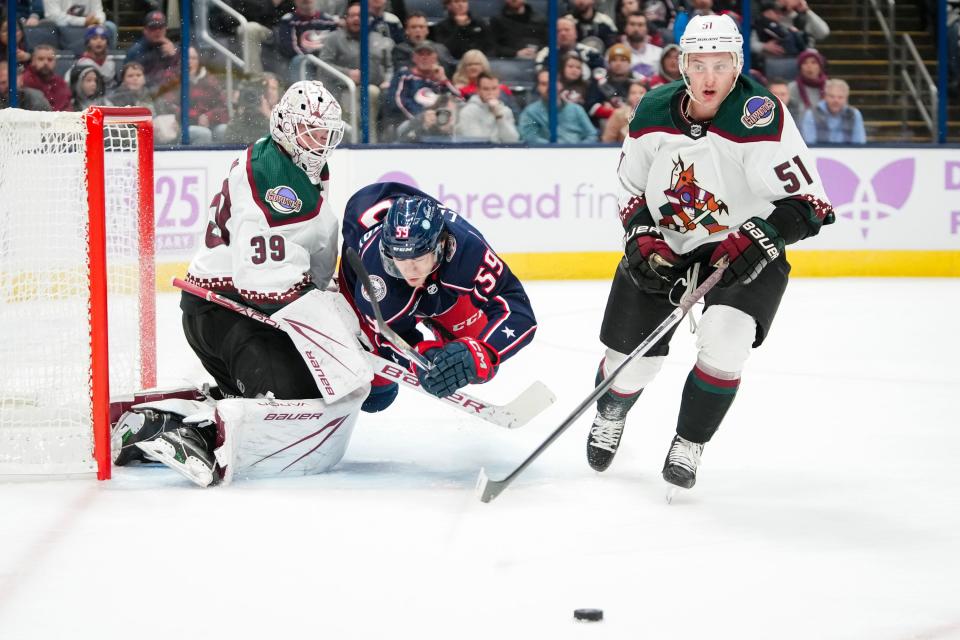 Nov 16, 2023; Columbus, Ohio, USA; Columbus Blue Jackets right wing Yegor Chinakhov (59) trips over Arizona Coyotes goaltender Connor Ingram (39) after behing hit by defenseman Troy Stecher (51) during the first period of the NHL hockey game at Nationwide Arena.