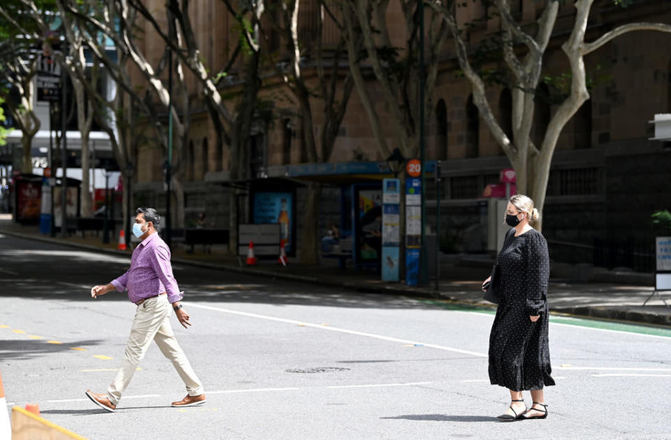 People are seen walking through the Brisbane CBD wearing masks in Brisbane, Australia. 