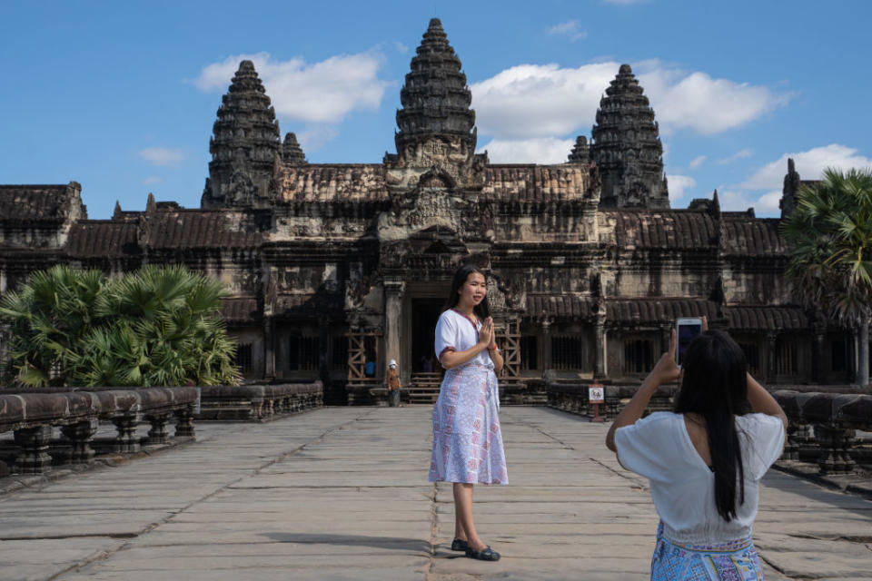 Tourists take photos in front of a largely empty Angkor Wat temple on December 10, 2021 in Siem Reap, Cambodia.<span class="copyright">Cindy Liu/Getty Images</span>