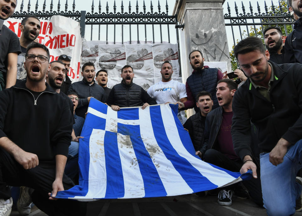 University students chant slogans as they hold a blood-stained Greek flag from the deadly 1973 student uprising during a rally in Athens, Friday, Nov. 17, 2023. The rally is, for the 50th anniversary of a 1973 student uprising that was crushed by Greece's military junta, that ruled the country from 1967-74.(AP Photo/Michael Varaklas)