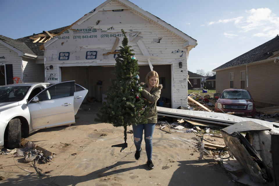 Kate Garrett retrieves a Christmas tree from her friend's destroyed home Tuesday, Dec. 14, 2021, in Bowling Green, Ky. The neighborhood was one of the hardest hit areas in the city after a tornado ripped through the weekend before. (AP Photo/James Kenney)