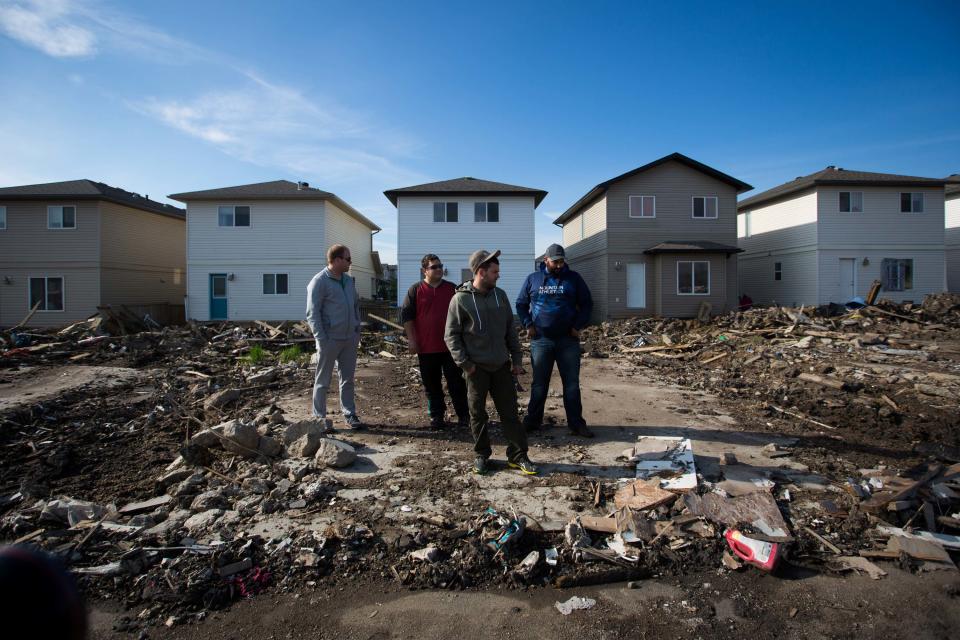 FILE PHOTO - Residents look over the damage in the Timberlea neighbourhood as thousands of evacuees who fled a massive wildfire begin to trickle back to their homes in Fort McMurray, Alberta, Canada on June 2, 2016. REUTERS/Topher Seguin/File Photo