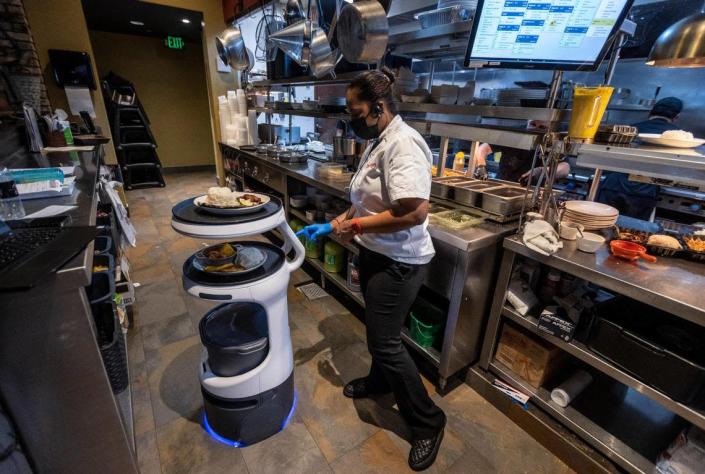 Yei Alayo, a worker in the kitchen at Sergio&#x002019;s restaurant in Kendall, programs a Servi robot server to deliver an order to a specific table inside the dining room, on May 21, 2021. This particular Servi robot was renamed ASTRO.