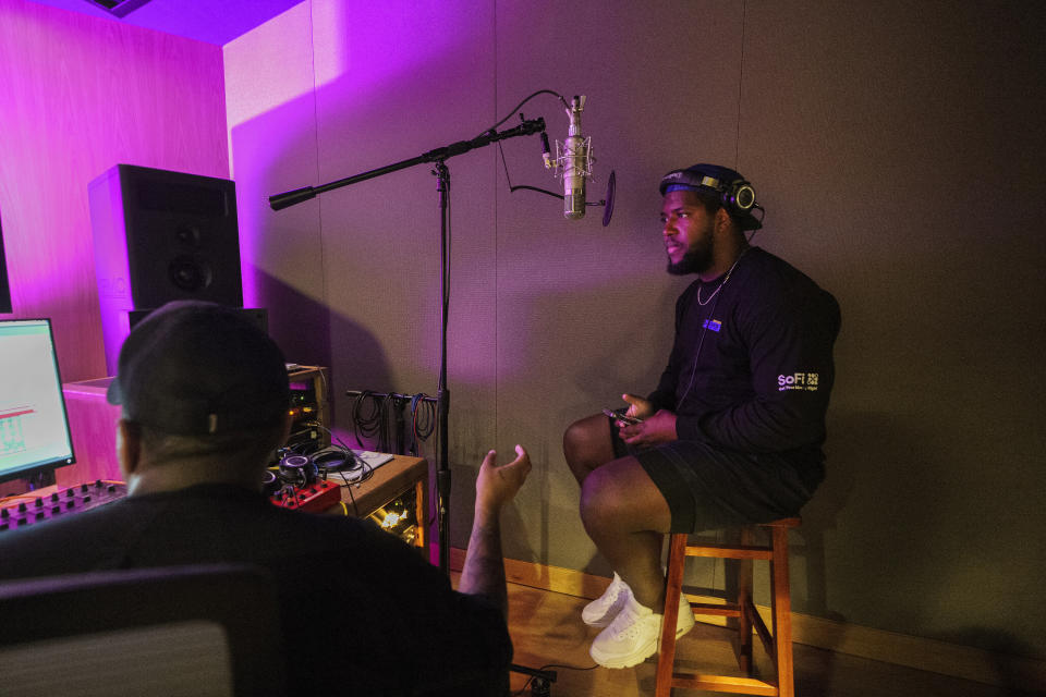 Producer and singing coach Derrick Milano, left, coaches Los Angeles Rams defensive liner Kobe Turner as he records an extended play at Interscope Records Studios In Santa Monica, Calif., Wednesday, June 21, 2023. The NFL, Interscope Geffen A&M Records and Electronic Arts Sports have partnered to empower players to pursue their passion of music and create the extended play project "Crowd Control." Songs from the EP were inserted into the video game "Madden NFL 24," released last month. (AP Photo/Damian Dovarganes)