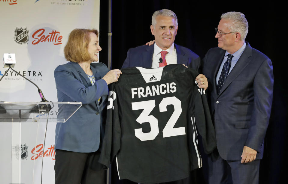 Ron Francis, center, is presented with a hockey jersey by Seattle Mayor Jenny Durkan, left, as Seattle Hockey Partners CEO Tod Leiweke looks on Thursday, July 18, 2019, in Seattle, as Francis is introduced as the first general manager for Seattle's yet-to-be-named NHL expansion team. Francis, a Hall of Famer and a two-time Stanley Cup winner, will have complete control of operations under Leiweke when the team debuts in 2021. (AP Photo/Ted S. Warren)