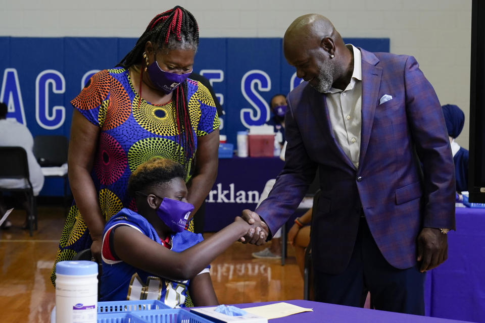Former Dallas Cowboy and Football Hall of Famer Emmitt Smith shakes hands with a COVID-19 vaccine recipient during a tour of vaccination site at Emmett J. Conrad High School in Dallas, Tuesday, June 29, 2021. (AP Photo/Carolyn Kaster, Pool)