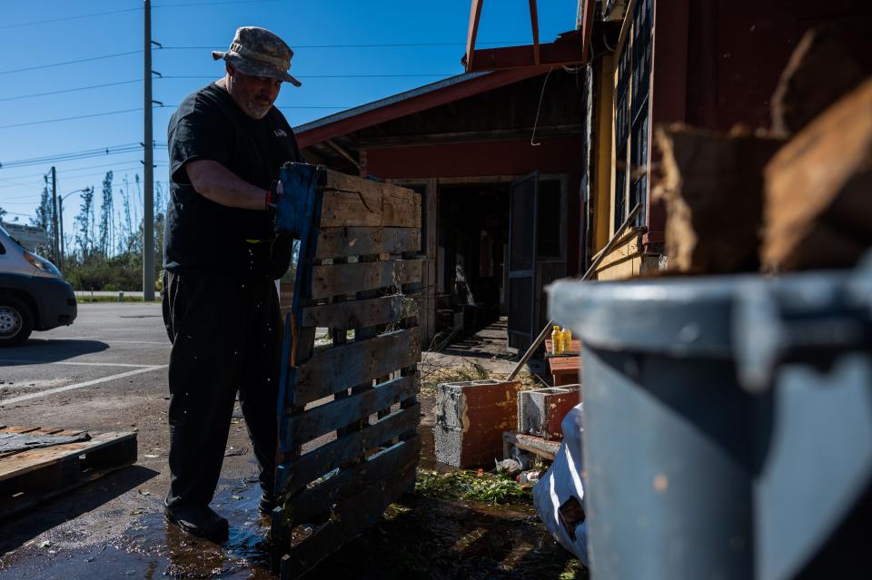 Jay Johnson, owner of Bubba's Roadhouse & Saloon and Bert's Bar & Grill, removes pieces of debris from the front of his restaurant after Hurricane Ian passed through the region Wednesday afternoon in Cape Coral, FL., on Friday, September 30, 2022.