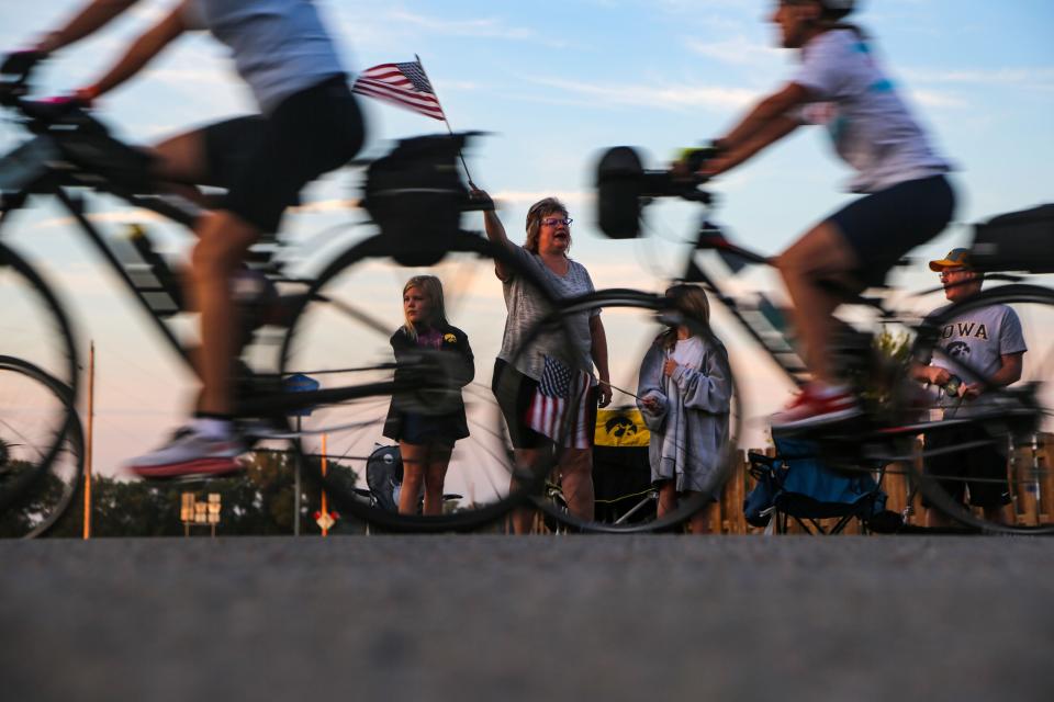 Joleen and Dean Lafrentz and their granddaughters Madelyn, 8, and Elizabeth, 10, wave flags as riders roll out of Sergeant Bluff on on the first day of RAGBRAI, Sunday, July 24, 2022.