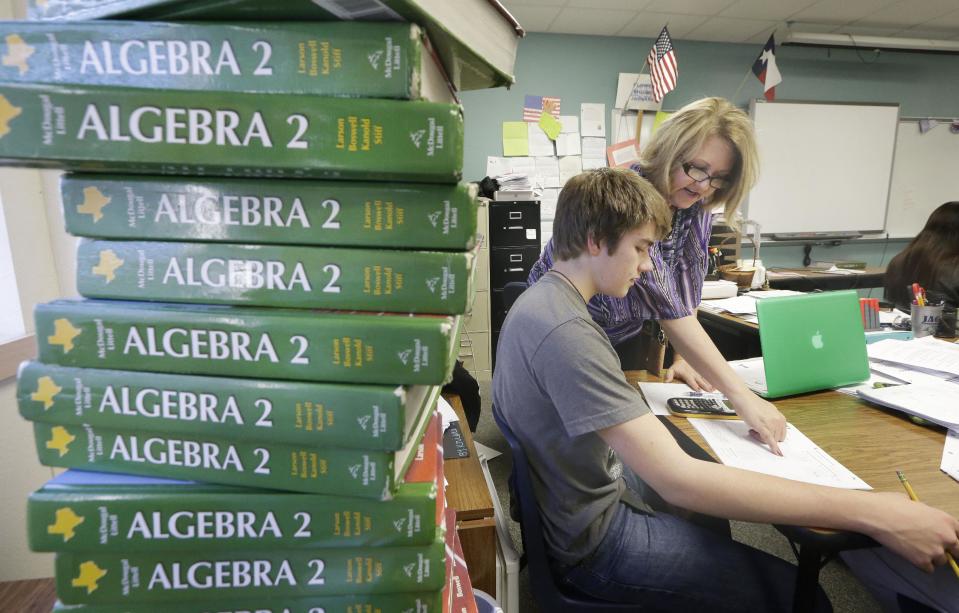 In a Wednesday, Jan. 15, 2014 photo, math teacher Tracy Popescu, right, helps high school junior Carter Buono, 17, with a problem in an algebra II class at Flower Mound High School in Flower Mound, Texas. Texas became the first state to require its high school students to take algebra II, betting tougher graduation standards would better prepare its youngsters for college and life beyond it. Since then, 16 other states and the District of Columbia have followed suit, and two more will by 2020. But Texas is now bucking the trend it began, abandoning advanced-math mandates to give high school students more flexibility to focus on vocational training for jobs that pay top dollar but don’t necessarily require a college degree. (AP Photo/LM Otero)