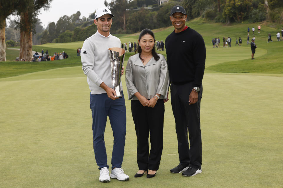 Joaquin Niemann, left, of Chile, poses with his trophy next to Megan Watanabe, center, president of The Riviera Country Club, and Tiger Woods, right, on the 18th green after winning the Genesis Invitational golf tournament at Riviera Country Club, Sunday, Feb. 20, 2022, in the Pacific Palisades area of Los Angeles. (AP Photo/Ryan Kang)