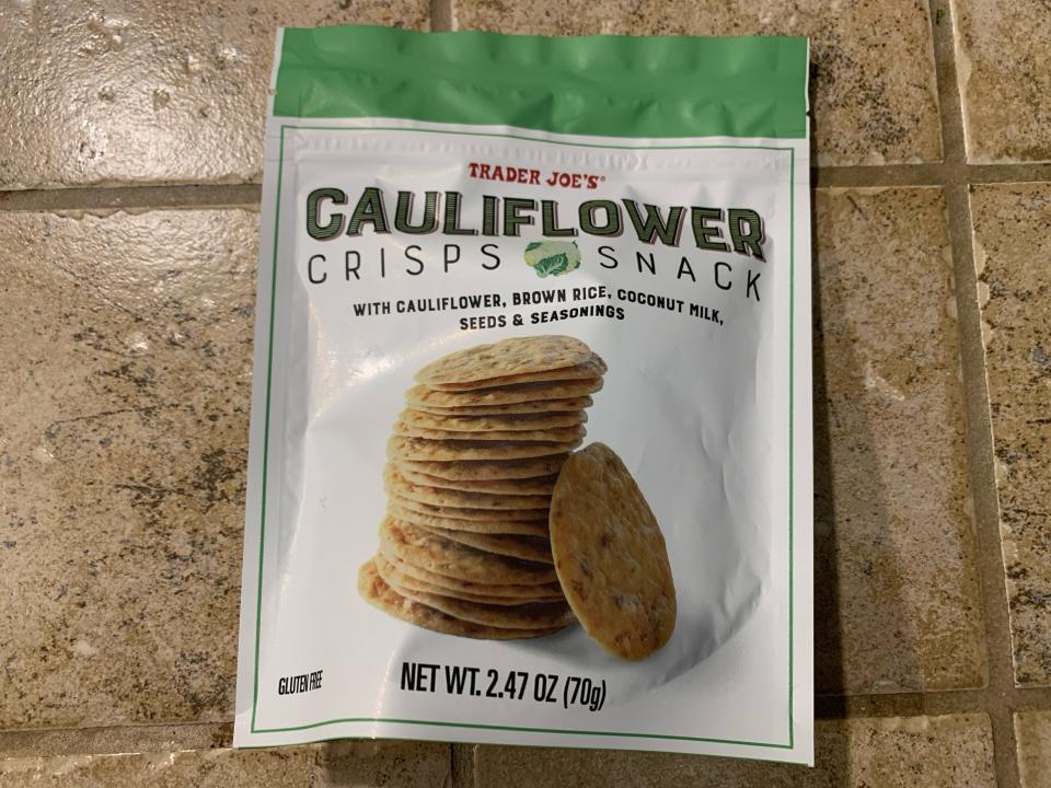 Trader Joe's cauliflower crisps in its original white and green bag against beige tile