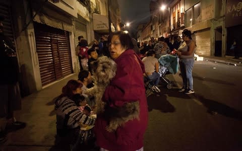 People gather on a street in downtown Mexico City during an earthquake - Credit: AFP