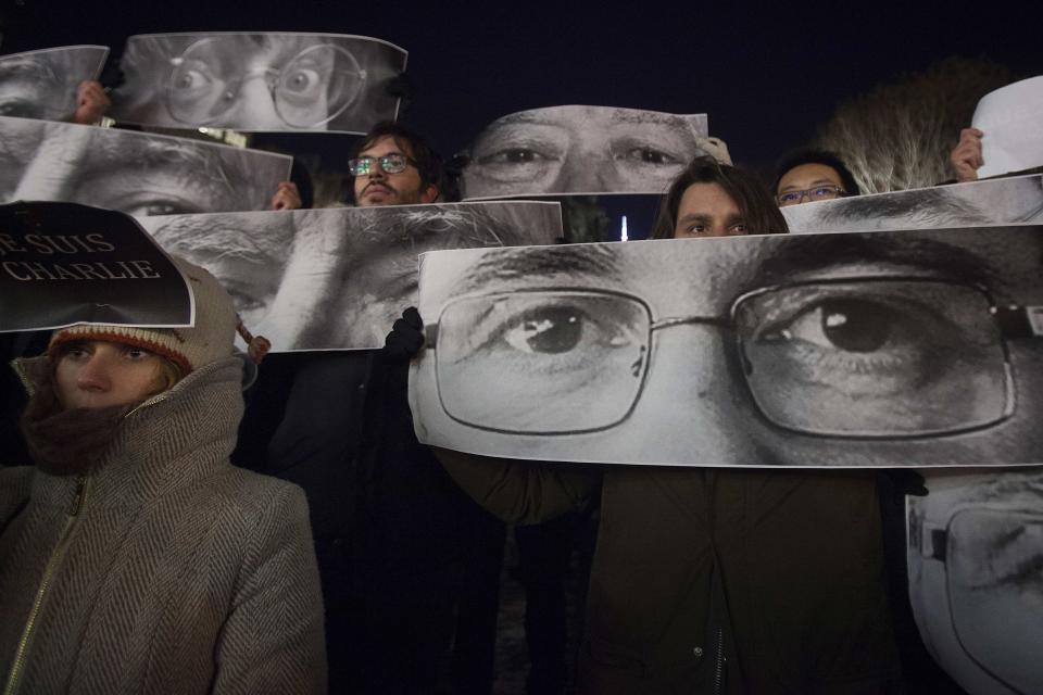 People hold up posters, which include Charlie Hebdo Editor Stephane Charbonnier (front), a cartoonist known as Charb, and Jean Cabut (back L), a cartoonist known as Cabu, during a vigil to pay tribute to the victims of a shooting, by gunmen at the offices of weekly satirical magazine Charlie Hebdo in Paris, in the Manhattan borough of New York January 7, 2015. Hooded gunmen stormed the Paris offices of the weekly satirical magazine known for lampooning Islam and other religions, shooting dead at least 12 people, including two police officers, in the worst militant attack on French soil in decades. REUTERS/Carlo Allegri (UNITED STATES - Tags: CIVIL UNREST CRIME LAW)