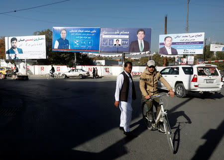 An Afghan man rides on his bicycle in front of election posters of parliamentarian candidates ahead of the elections in Kabul, Afghanistan October 18, 2018. REUTERS/Omar Sobhani