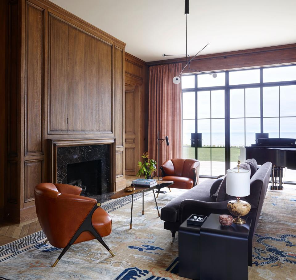 A Chinese Art Deco rug in the oak-paneled music room pulls together midcentury Karpen of California lounge chairs, a Werkstätte cocktail table by Carl Auböck, and a modern chandelier by Michael Anastassiades.