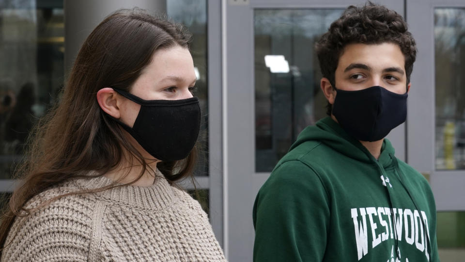 While wearing protective masks due to the COVID-19 outbreak, Lucy Vitali, who portrays Juliet, left, stands with Alex Mansour, who portrays Romeo, outside the auditorium after working on their virtual performance of Shakespeare's "Romeo and Juliet," at Westwood, Mass. High School, Monday, Nov. 16, 2020, in Westwood. The production, which would usually be presented onstage, shifted to a virtual audience due to the pandemic. (AP Photo/Charles Krupa)