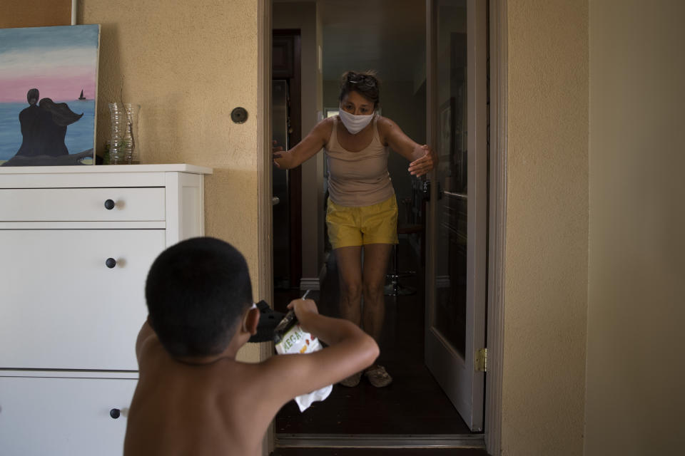 Rose Matute, a mother of ICU nurse Jackie Vargas, and Vargas's 6-year-old son, Kai, give each other an air hug at Matute's home in Lakewood, Calif., Saturday, July 11, 2020. The 39-year-old nurse, who works in St. Jude Medical Center's COVID-19 unit, doesn't hug her mother-in-law, who is taking care of her children. Through a glass door, she visits her own mom. (AP Photo/Jae C. Hong)