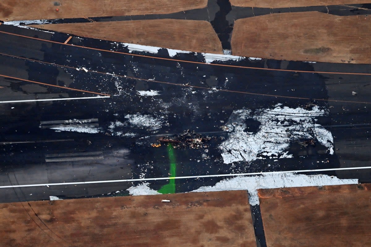 n this aerial image, the debris of MA-722, a Bombardier Dash-8, Japan Coast Guard (JCG) aircraft is seen a day after the collision with a Japan Airlines Flight 516 at Haneda Airport (The Asahi Shimbun via Getty Imag)