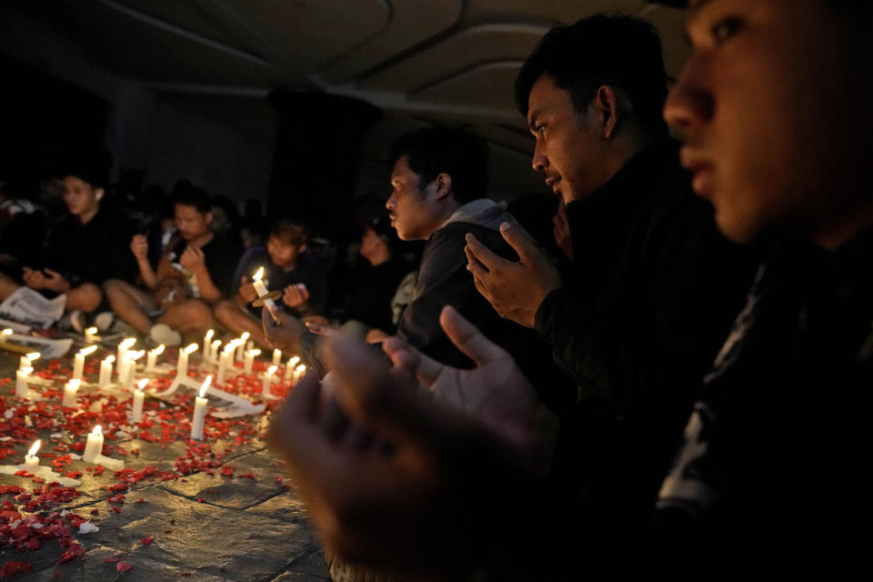 Soccer fans pray during a candle light vigil for the victims of Saturday's stampede, in Tangerang, Indonesia, Tuesday, Oct. 4, 2022. Police firing tear gas inside a stadium in East Java on Saturday in an attempt to stop violence after an Indonesian soccer match triggered a disastrous crush of fans making a panicked, chaotic run for the exits, leaving at a number of people dead, most of them trampled upon or suffocated. (AP Photo/Dita Alangkara)