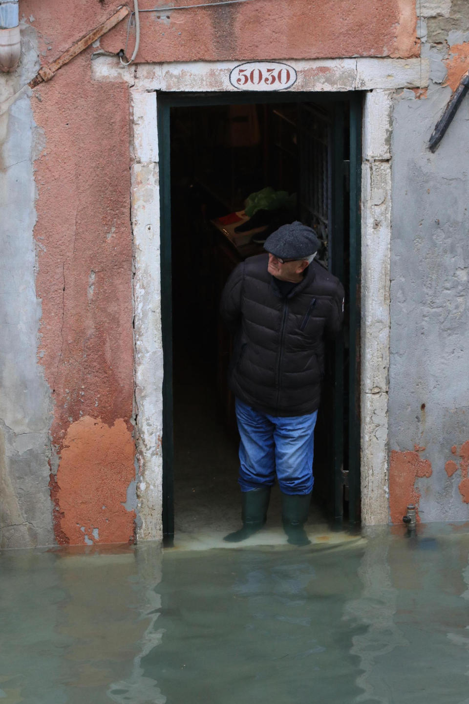 A man looks out of a doorway at the flooding in Venice, Italy, Friday, Nov. 15, 2019. Exceptionally high tidal waters returned to Venice on Friday, prompting the mayor to close the iconic St. Mark's Square and call for donations to repair the Italian lagoon city just three days after it experienced its worst flooding in 50 years. (Emiliano Crespi/ANSA via AP)