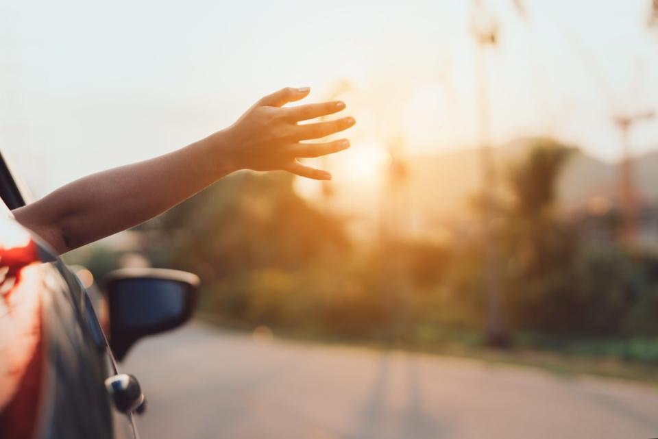 view of road with hand hanging out of car window